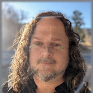 Male face looking off to the side. Long, curly hair.